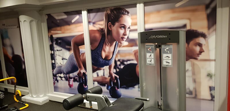 An image of a wall graphic in a gym that shows people in a plank.
